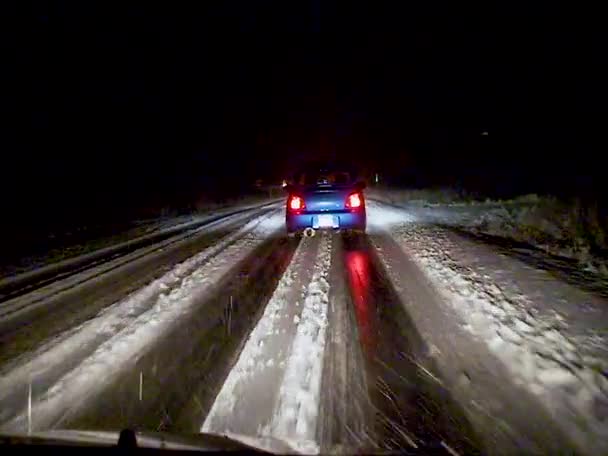 車は米国の滑りやすい雪の道で夜にゆっくり運転します — ストック動画