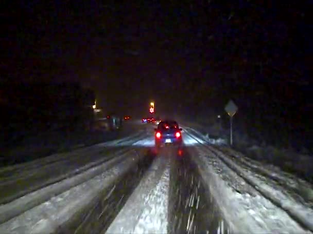 車は米国の滑りやすい雪の道で夜にゆっくり運転します — ストック動画