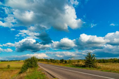 White cumulus thunderclouds in the sky over a highway, Ukraine