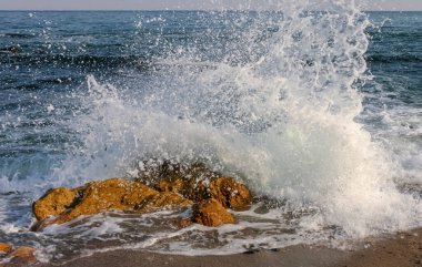Waves break on a stone and white splashes of water fly into the air, the Black Sea