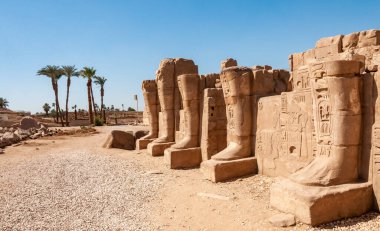 EGYPT, LUXOR - Mart 01, 2019: Mısır 'ın Luxor kentindeki eski bir Mısır tapınağının kalıntılarının toprakları üzerindeki palmiye ağaçları