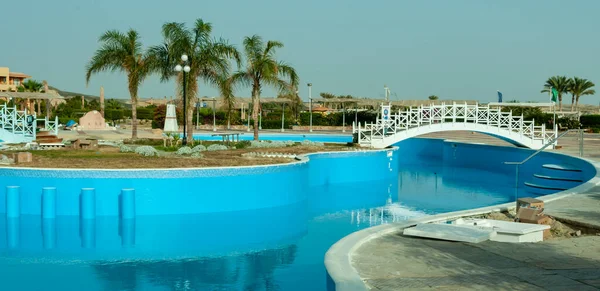 stock image EGYPT, MARS ALAMA - FEBRUARY 02, 2019: interior with white wooden footbridge over the swimming pool on the territory of the hotel complex in Mars Alama