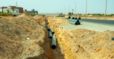 EGYPT, MARSA ALAM-FEBRUARY 24, 2019: Mısır 'ın küçük bir kasabasında yol boyunca kumda plastik su boruları döşemek