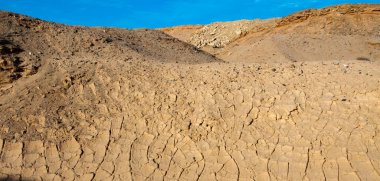 Çölde kurumuş bir su deresinin yatağında kurumuş kırmızı kil, Mısır.