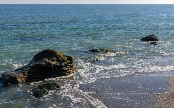 海浪带着白沫在沙滩上翻滚 阳光反射在水面上 — 图库照片