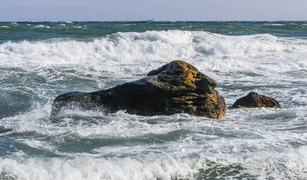 波が石の上で壊れ 水の白い飛沫が空気中に飛び込み — ストック写真