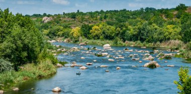 Lastik bir teknede bir balıkçı Ukrayna 'nın güneyindeki Bug Nehri' nin ortasındaki kaya yarıklarının arkasında balık yakalar.