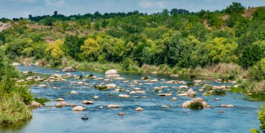 Lastik bir teknede bir balıkçı Ukrayna 'nın güneyindeki Bug Nehri' nin ortasındaki kaya yarıklarının arkasında balık yakalar.