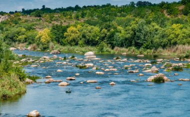 Lastik bir teknede bir balıkçı Ukrayna 'nın güneyindeki Bug Nehri' nin ortasındaki kaya yarıklarının arkasında balık yakalar.