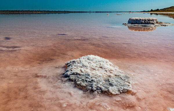 Salt Lake. Self-settling sodium chloride salt on rocks near the shore. Hypersaline water in a drying lake is an environmental problem. Kuyalnik Estuary, Ukraine