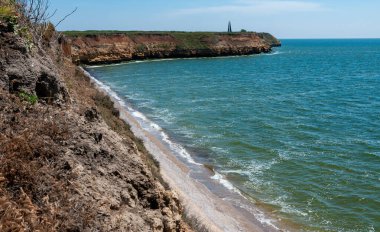 Ukrayna 'nın Berezan adasında yaban bozkır bitkileriyle kaplı dik kayalık ve kabuklu kaya kıyıları.
