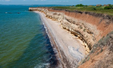 Ukrayna 'nın Berezan adasında yaban bozkır bitkileriyle kaplı dik kayalık ve kabuklu kaya kıyıları.