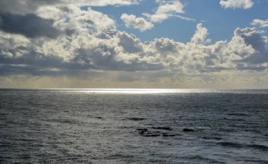 The sun's rays break through thick clouds over the Pacific Ocean, a sunspot is all over the water