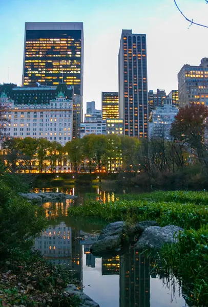 New York, ABD - 18 Kasım 2009: Manhattan Park, ABD 'de gölün kenarından parlayan gökdelenlerin akşam manzarası