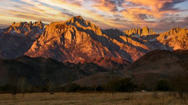 Karla kaplı tepeleri olan kayalık dağların zirveleri akşam güneşiyle aydınlanıyor, Sierra Nevada Dağları, Kaliforniya, ABD