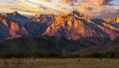 Karla kaplı tepeleri olan kayalık dağların zirveleri akşam güneşiyle aydınlanıyor, Sierra Nevada Dağları, Kaliforniya, ABD