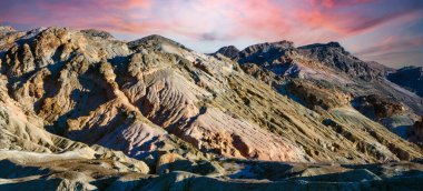 Ölüm Vadisi NP, Kaliforniya 'daki renkli tepelerin panoramik görüntüsü. Tepeler mor, mavi, yeşil, sarı ve kahverengi tonlarıyla boyanarak güzel ve soyut bir manzara yaratıyor.