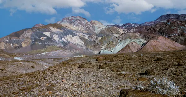 Ölüm Vadisi NP, Kaliforniya 'daki renkli tepelerin panoramik görüntüsü. Tepeler mor, mavi, yeşil, sarı ve kahverengi tonlarıyla boyanarak güzel ve soyut bir manzara yaratıyor.