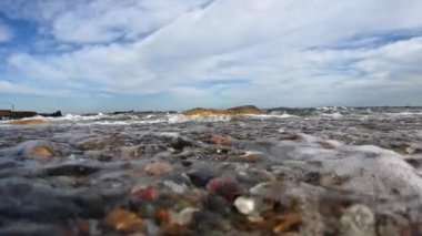 Kumlu bir sahilde dalgalar bir video kamera, kum ve çakıl taşları Karadeniz 'de dalgalanan dalgalarda dalgalanıyor, Odessa