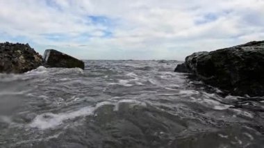 Suda hava kabarcıkları olan dalgalar akın ediyor. Kamera ve taşlar midye ve alglerle kaplanıyor. Karadeniz 'deki Fırtına.