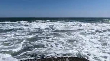 Güneşli bir günde denizde bir fırtına, suyun yüzeyinde beyaz köpük.