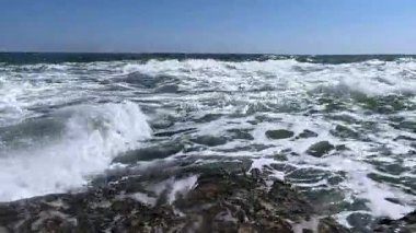 Güneşli bir günde denizde bir fırtına, suyun yüzeyinde beyaz köpük.