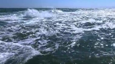 Güneşli bir günde denizde bir fırtına, suyun yüzeyinde beyaz köpük.