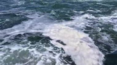 Güneşli bir günde denizde bir fırtına, suyun yüzeyinde beyaz köpük.