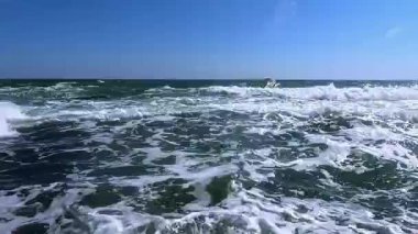 Güneşli bir günde denizde bir fırtına, suyun yüzeyinde beyaz köpük.