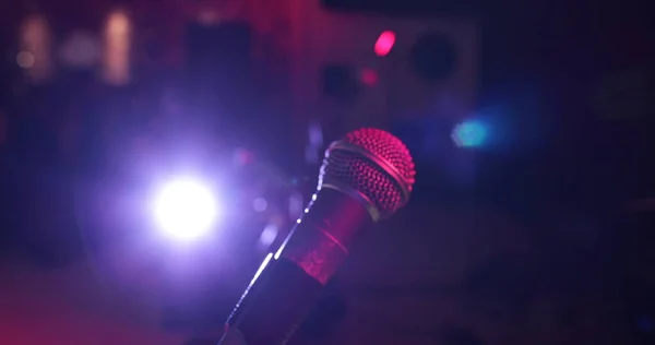 Close up of a professional vocal wire microphone on a microphone stand on stage.