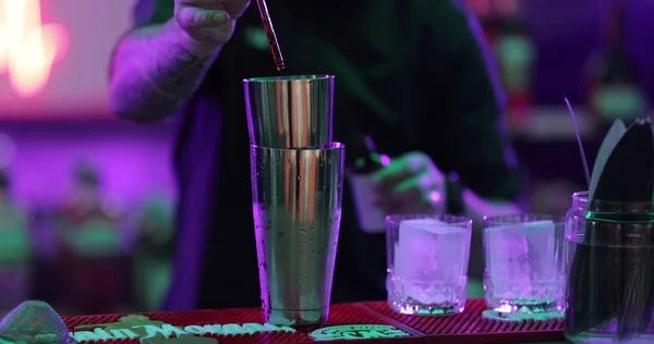 4Kプロの男性バーテンダーは カクテルシェーカーから混合ブルーアルコールカクテルドリンクをナイトクラブのバーカウンターでショットガラスに注ぎます お客様にアルコール飲料を提供するミクロジストバーマン — ストック写真