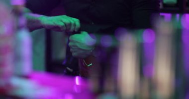 4K profesyonel barmen kokteyl bardağından barın tezgahına karışık mavi likör kokteyli dolduruyor. Barmen müşteriye alkol servisi yapıyor.