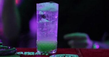 4K profesyonel barmen kokteyl bardağından barın tezgahına karışık mavi likör kokteyli dolduruyor. Barmen müşteriye alkol servisi yapıyor.