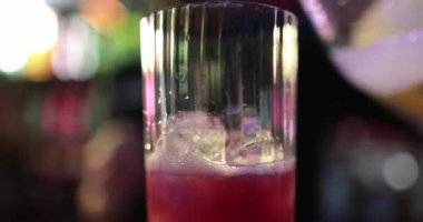 4K profesyonel barmen kokteyl bardağından barın tezgahına karışık mavi likör kokteyli dolduruyor. Barmen müşteriye alkol servisi yapıyor.