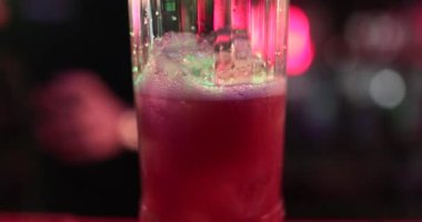 4K profesyonel barmen kokteyl bardağından barın tezgahına karışık mavi likör kokteyli dolduruyor. Barmen müşteriye alkol servisi yapıyor.