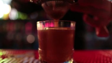 4K profesyonel barmen kokteyl bardağından barın tezgahına karışık mavi likör kokteyli dolduruyor. Barmen müşteriye alkol servisi yapıyor.