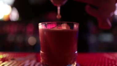 4K profesyonel barmen kokteyl bardağından barın tezgahına karışık mavi likör kokteyli dolduruyor. Barmen müşteriye alkol servisi yapıyor.