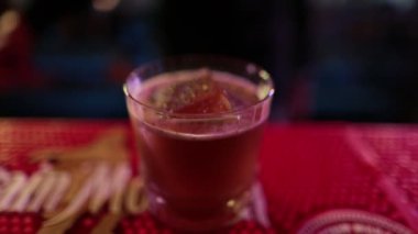 4K profesyonel barmen kokteyl bardağından barın tezgahına karışık mavi likör kokteyli dolduruyor. Barmen müşteriye alkol servisi yapıyor.