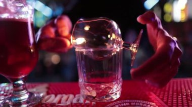 4K profesyonel barmen kokteyl bardağından barın tezgahına karışık mavi likör kokteyli dolduruyor. Barmen müşteriye alkol servisi yapıyor.