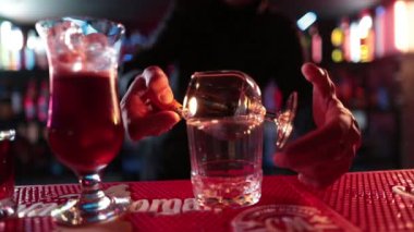 4K profesyonel barmen kokteyl bardağından barın tezgahına karışık mavi likör kokteyli dolduruyor. Barmen müşteriye alkol servisi yapıyor.