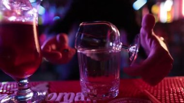 4K profesyonel barmen kokteyl bardağından barın tezgahına karışık mavi likör kokteyli dolduruyor. Barmen müşteriye alkol servisi yapıyor.