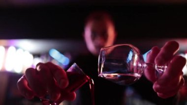 4K profesyonel barmen kokteyl bardağından barın tezgahına karışık mavi likör kokteyli dolduruyor. Barmen müşteriye alkol servisi yapıyor.