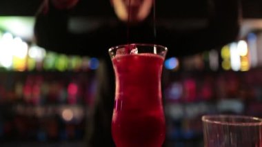 4K profesyonel barmen kokteyl bardağından barın tezgahına karışık mavi likör kokteyli dolduruyor. Barmen müşteriye alkol servisi yapıyor.