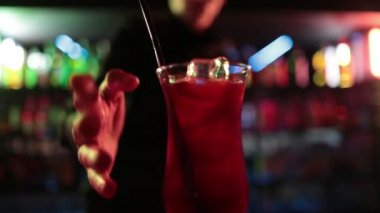 4K profesyonel barmen kokteyl bardağından barın tezgahına karışık mavi likör kokteyli dolduruyor. Barmen müşteriye alkol servisi yapıyor.