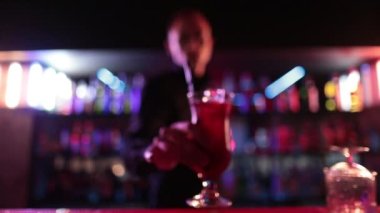 4K profesyonel barmen kokteyl bardağından barın tezgahına karışık mavi likör kokteyli dolduruyor. Barmen müşteriye alkol servisi yapıyor.