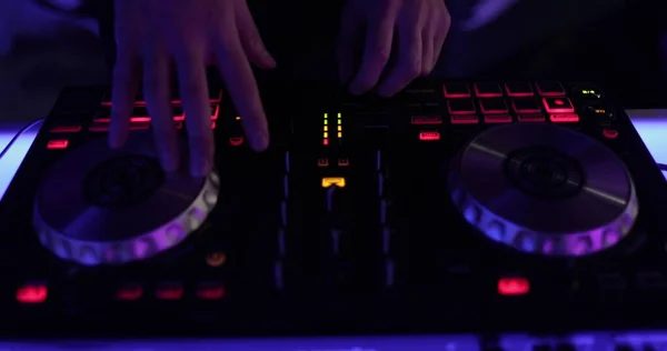 Hands and DJ console at work. DJ playing at a party, close-up.