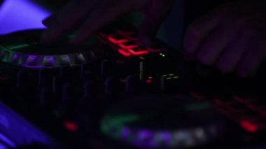 Eller ve DJ konsolu iş başında. DJ bir partide çalıyor, yakın plan..