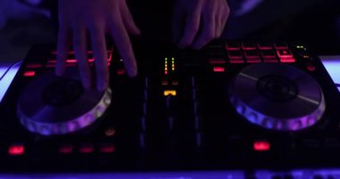 Eller ve DJ konsolu iş başında. DJ bir partide çalıyor, yakın plan..