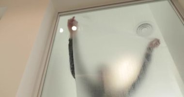 Adamın biri cam kapıyı opak yapmak için klinikteki cam kapıya buzlu bir kaplama serpiştiriyor. Cama mat kaplama uyguluyorum..