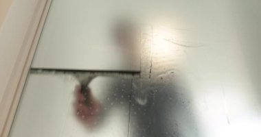 Adamın biri cam kapıyı opak yapmak için klinikteki cam kapıya buzlu bir kaplama serpiştiriyor. Cama mat kaplama uyguluyorum..